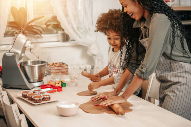 girl making gingerbread cookies with mom - pastry cutter family holiday child imagens e fotografias de stock