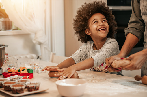 Cute 5 years old girl making cookies for Christmas with her mom.