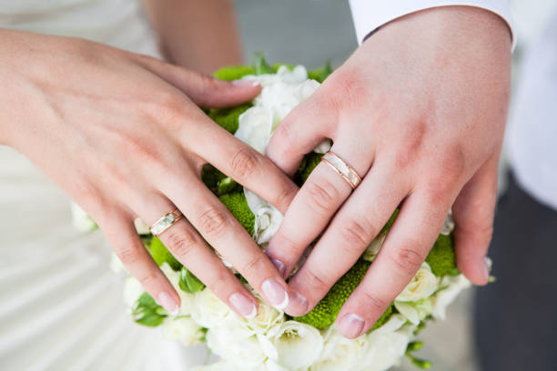 istock Groom and bride holding hands with wedding rings 1195027265