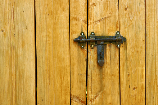 Iron latch and yellow wooden gate closeup on the ranch house for background or texture