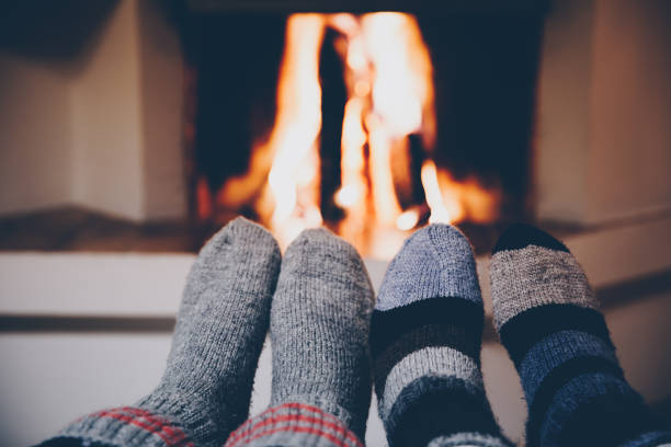 暖炉のそばにウールのストライプの靴下の足。休日の夜にクリスマス暖炉でリラックス。 - mulled wine christmas tea heat ストックフォトと画像