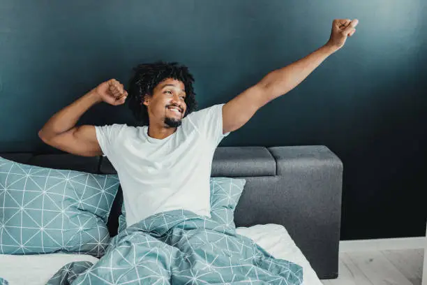 Young man in the morning waking up and stretching