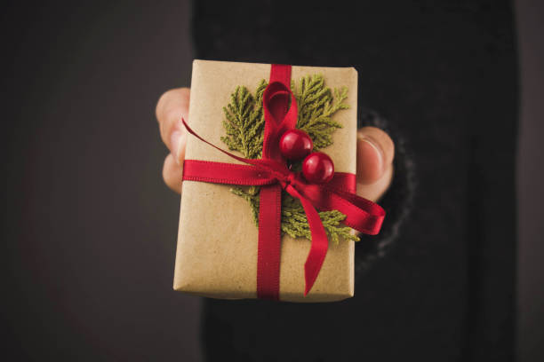 istock Woman with dark sweater holding a Christmas present. 1195036138