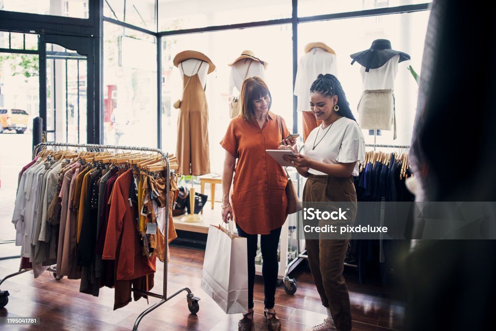 This is how you sign up and receive amazing offers Shot of a shop assistant using a digital tablet while assisting a customer in a boutique Retail Stock Photo