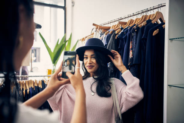 この帽子を手に入れるべきか聞くために彼氏にメールを送っている - hat shop ストックフォトと画像