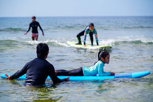 Father teaching his young daughter how to surf in Okinawa, Japan