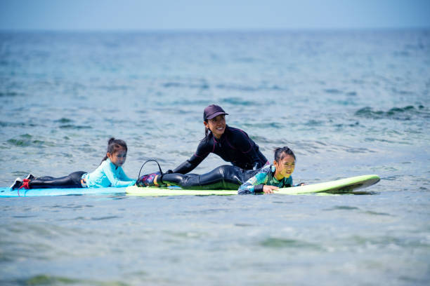 istock Mother teaching her young daughters how to surf during a tropical vacation 1195045784