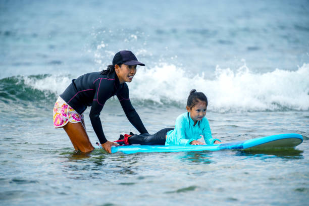 istock Mother teaching her young daughter how to surf during a tropical vacation 1195045793