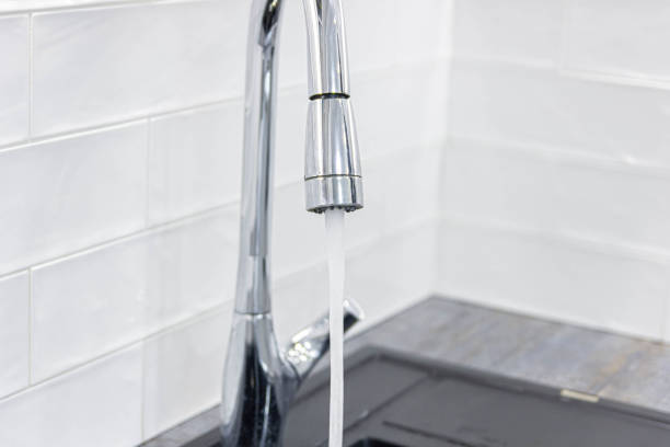 istock pouring water from a modern faucet in the kitchen. Water saving concept. 1195046248
