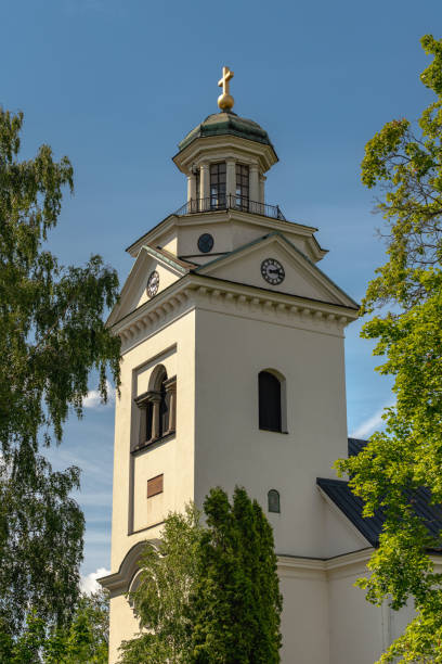 istock White church tower in evening sunlight surrounded by green foliage 1195051394