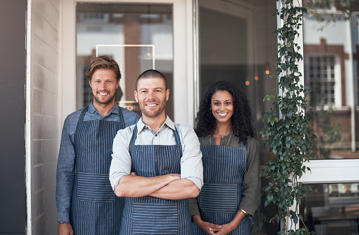 Portrait of a group of coffee shop employees standing outside their cafe