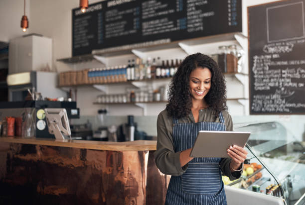 Technology allows me to simplify all my business operations Shot of a young woman using a digital tablet while working in a cafe small business owner stock pictures, royalty-free photos & images