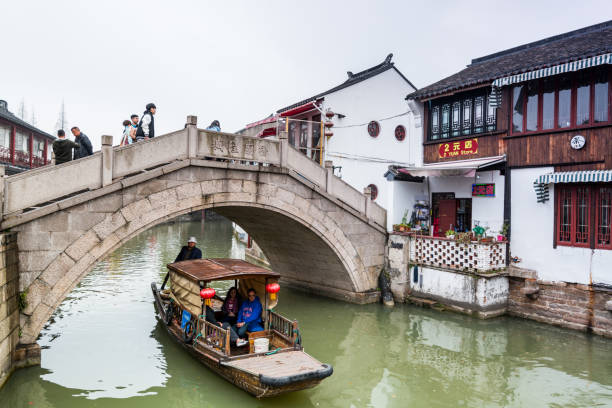 A tour boat passing through a stone bridge in Zhujiajiao, an ancient water town in Shanghai, built during Ming and Qing Dynasties, the various spans are built of wood, marble and stone A tour boat passing through a stone bridge in Zhujiajiao, an ancient water town in Shanghai, built during Ming and Qing Dynasties, the various spans are built of wood, marble and stone Zhujiajiao stock pictures, royalty-free photos & images