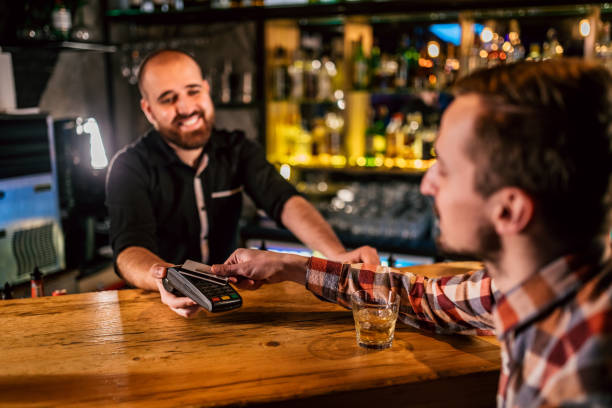 istock Man paying with mobile phone in bar 1195054952