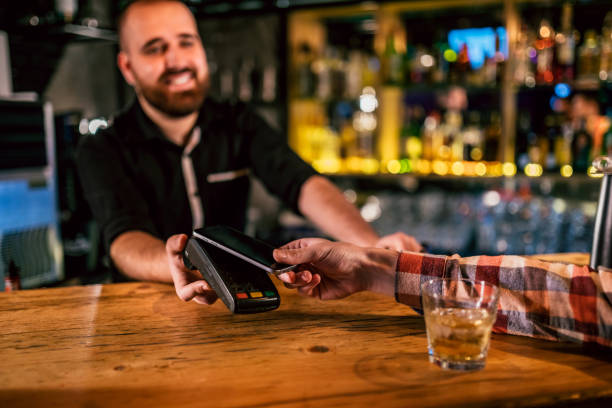istock Man paying with mobile phone in bar 1195054970