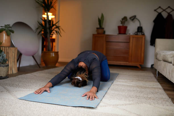 istock Woman in the child's pose while practicing yoga at home 1195055156