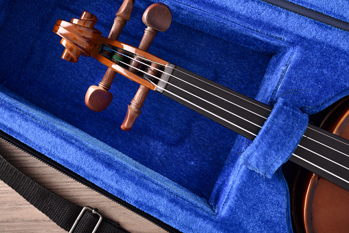 Student violin in case on wooden table detail. Top view. Horizontal composition.