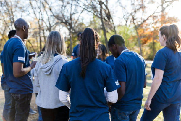 istock Standing in circle, unrecognizable park cleanup volunteers wait for instructions 1195063181
