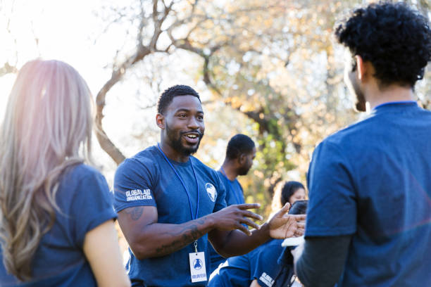 istock Three diverse volunteers talk together before starting park cleanup 1195063227