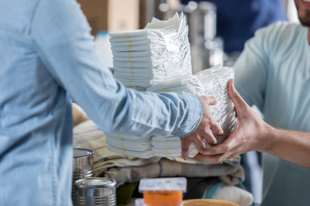 Woman donates diapers during clothing drive During a charity event, an unrecognizable woman donates a large stack of disposable diapers. A male volunteer receives the donation. Diaper stock pictures, royalty-free photos & images