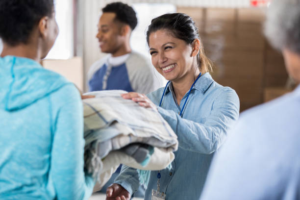 sukarelawan tersenyum menerima selimut selama penggerak pakaian - selimut seprai foto potret stok, foto, & gambar bebas royalti