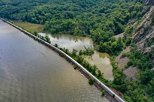 Aerial view of a freight train traveling along a lush coastal, mountainous landscape