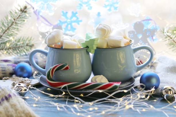 istock Two cups with a drink, marshmallows, caramel sticks, Christmas decor, illuminations on a wooden surface 1195066385