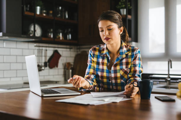 istock Young woman sitting in kitchen and going through her financials 1195066700