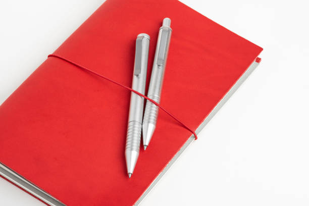 istock Red Leather Journal Cover With Two Ballpoint Pens 1195069933