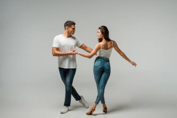 dancers in denim jeans dancing bachata on grey background