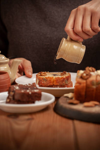 istock Hand pouring dark chocolate syrup on sweet bread cake. 1195082116