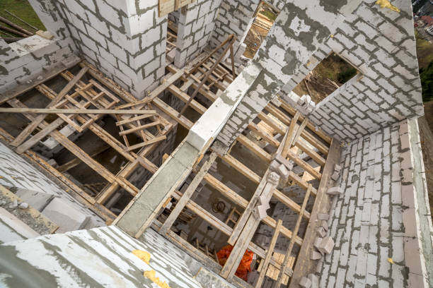 View from above of future multi stored cottage energy saving walls of large white hollow foam insulation blocks and temporary wooden scaffolding frame. Construction masonry, modern technology concept. vista desde arriba de futuras paredes de ahorro de energía de cabañas múltiples almacenadas de grandes bloques de aislamiento de espuma hueca blanca y marco de andamios de madera temporales. albañilería de construcción, concepto de tecnología modern