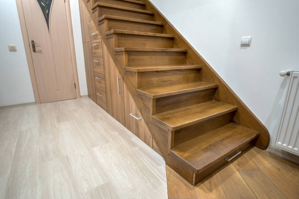 istock Modern architecture interior with luxury hallway with glossy wooden stairs in multi-storey house. Custom built pullout cabinets on glides in slots under stairs. Use of space for storage. 1195090562