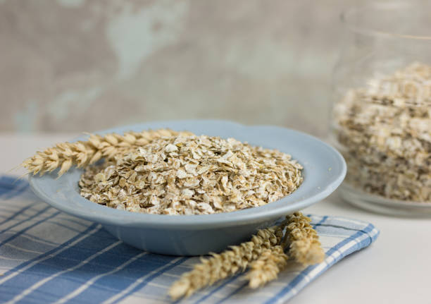 istock raw oatmeal in a spoon and in a plate on the table. place for text 1195090679