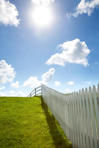 old fences and light poles with green grass field and sky background