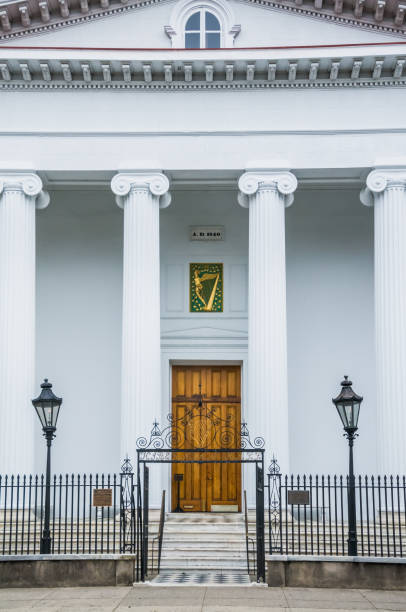 Charleston, South Carolina, USA -March 26, 2019- The wooden doorway of Hibernian Hall is flanked by gas lights and surrounded by an ornate wrought iron fence and gate. Built in 1840, it is  a fine example of Greek Revival architecture