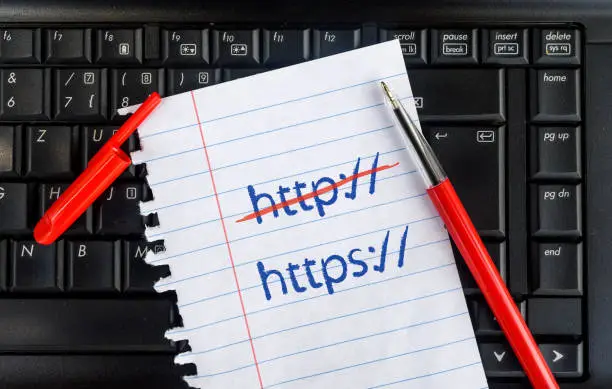 Photo of Paper width https, Crossed Out http and pencil on laptop keyboard