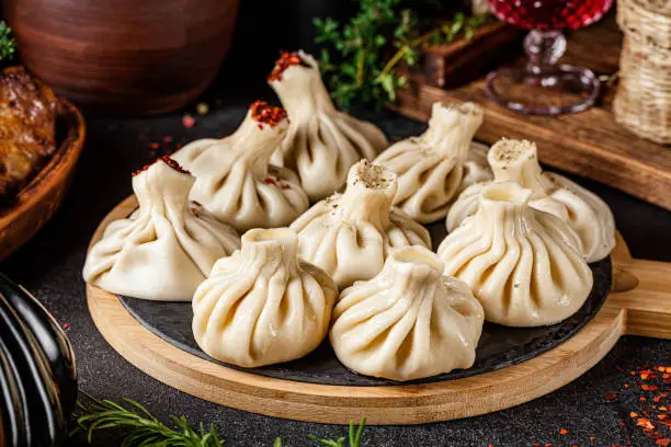 Photo of National Georgian cuisine. Khinkali with meat. Khinkali on a wooden board close-up.