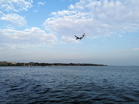 Istanbul, Turkey - October 28, 2019: A plane above Marnara Sea people are near by sea side of Florya. People are cycling and walking in a sunny day near by sea side of Florya.