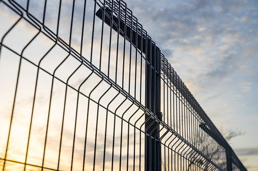 Steel grating fence made with wire on blue sky background. Sectional fencing installation