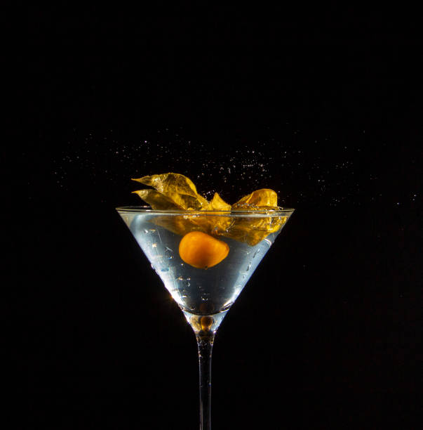 A Peruvian ground cherry, also called physalis, in an illuminated cocktail glass stock photo