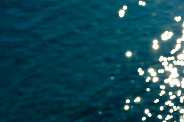 Blurred blue sea water surface with bright golden sparkles background