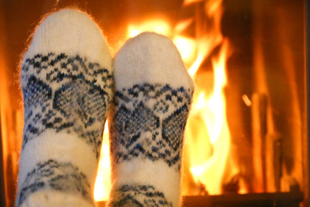istock Feet in wool socks warming at the fireplace 1195113722