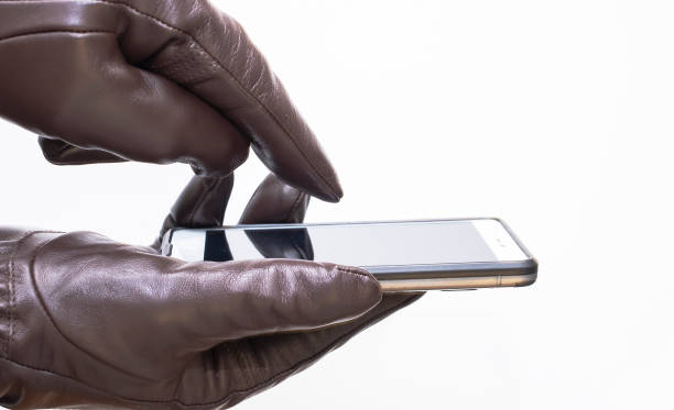 istock Hands of a man in leather gloves, using a smartphone. Touch leather gloves. 1195115421