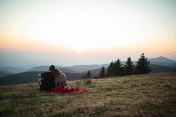 istock Couple sitting in a meadow and watching the sunset 1195115528