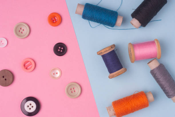 istock Colored threads and buttons on a blue and pink background. 1195118750