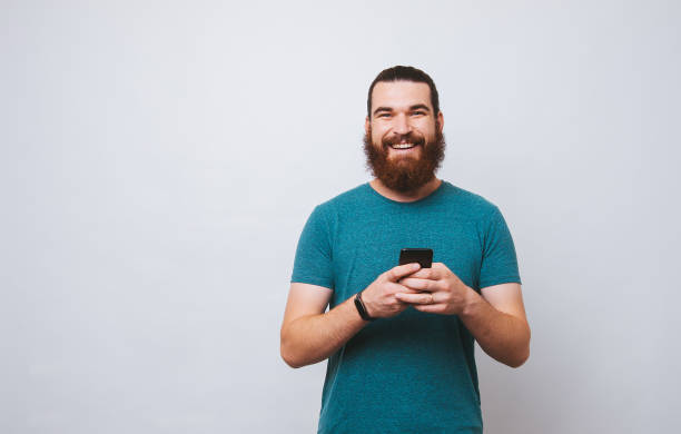 istock Smiling bearded man self accepted looking at the camera holding his mobile phone. 1195120826