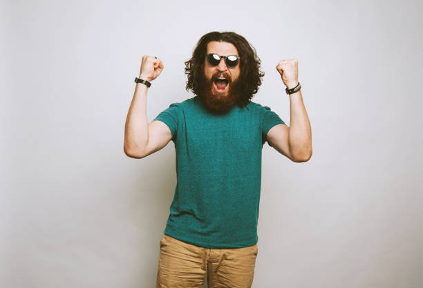 istock Young long haired bearded man wearing glasses smiling laughing making a winning gesture. 1195120876