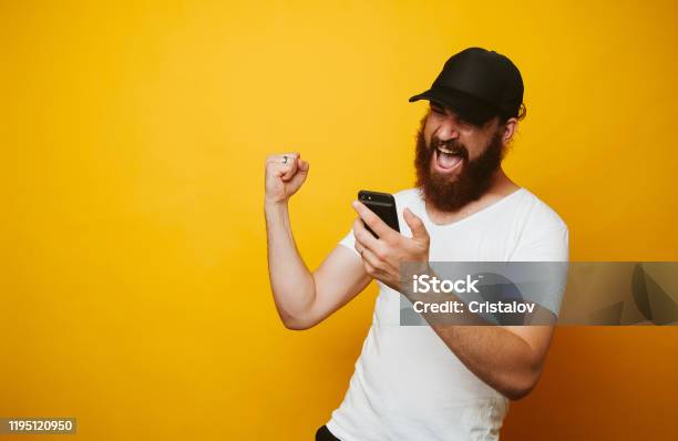 Happy Bearded Man Celebrate Success And Looking At Phone Stock Photo - Download Image Now