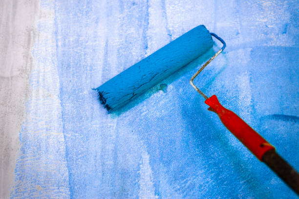 istock Long handle roller brush applying primer paint on Blue wall, building and home renovation concept 1195122776